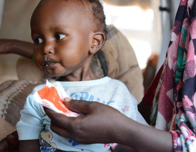 A child eats ready-to-use therapeutic food to treat malnutrition in Sudan.