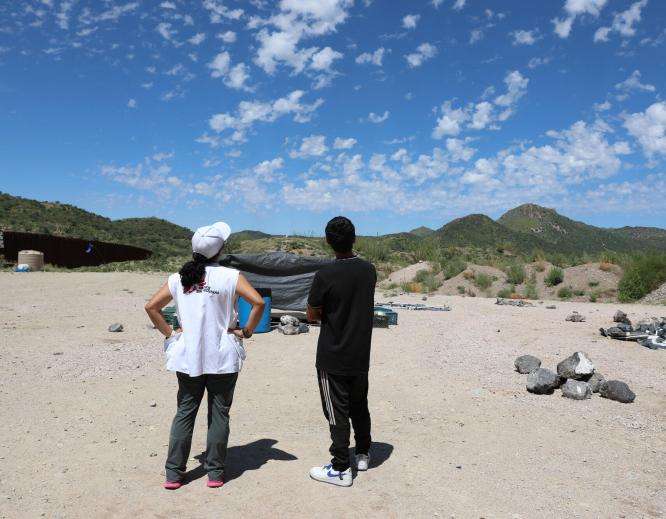 Project Coordinator Belen Ramirez and a 17-year-old boy form Bangladesh look at a helicopter flying overhead at the End of the Wall camp in Arizona.