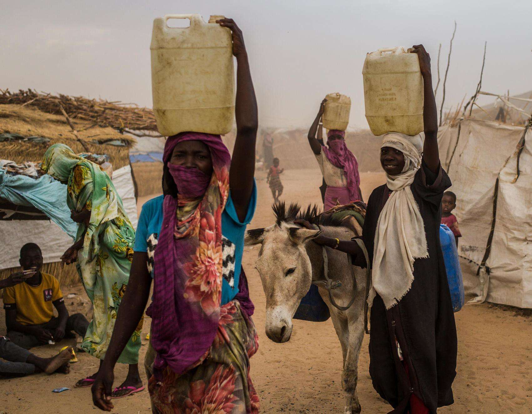 Sudanese refugees carry water on their heads in Chad.