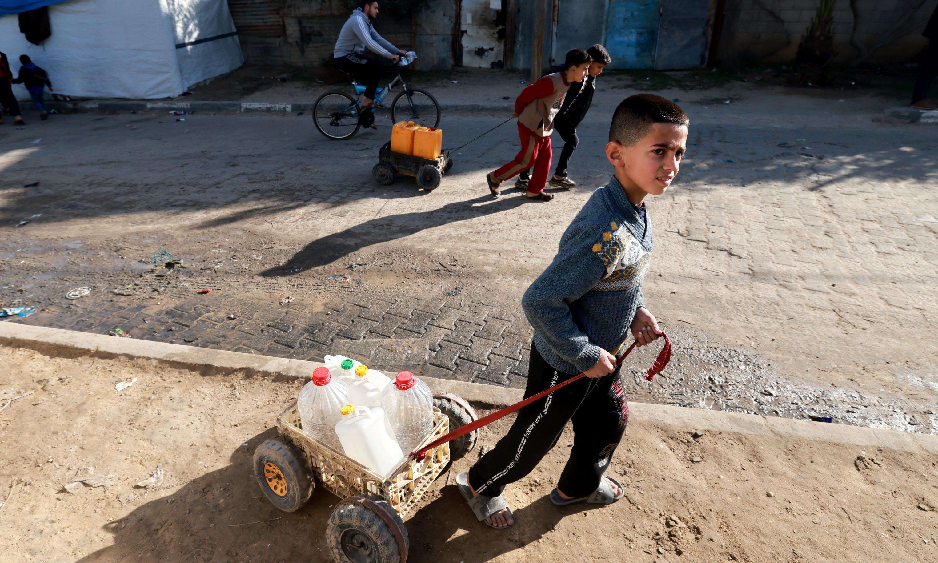 A Palestinian child fetches water from a distribution point in Rafah, Gaza.