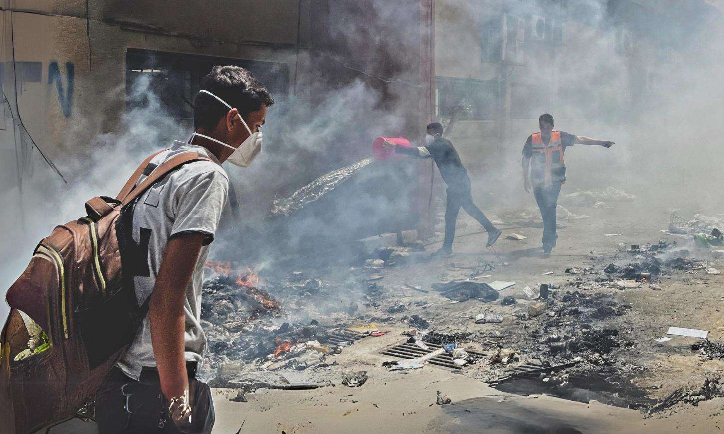 Palestinians walk through smoke in the streets of Gaza.