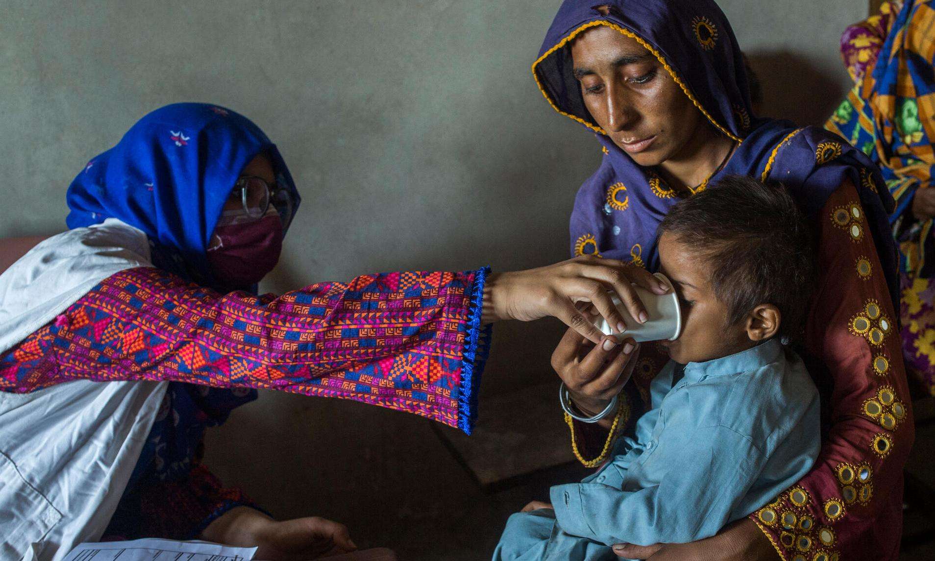 An MSF staff member treats a child carried by their mother in Pakistan after the floods.