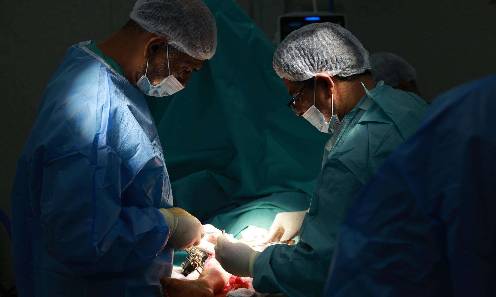 Doctors perform surgery on a patient in a dark room at Nasser Hospital in Gaza