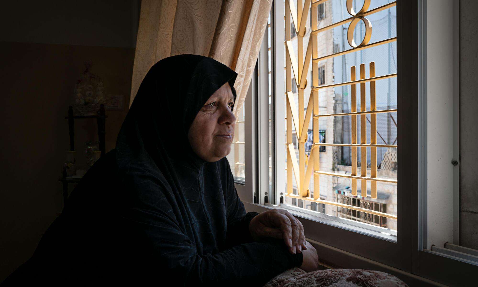 A Palestinian woman looks out from her window in Hebron, occupied West Bank.