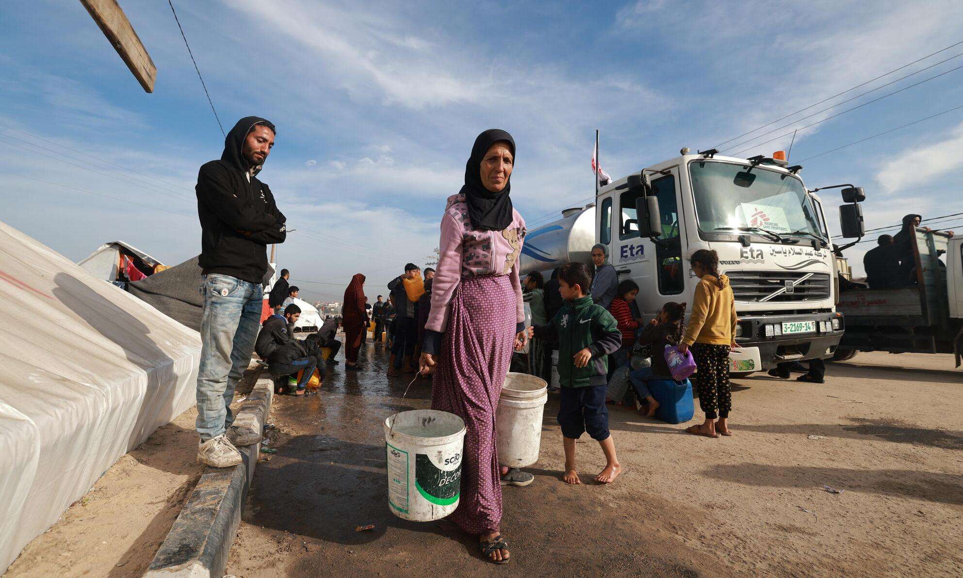 A Palestinian woman carries water to her tent after an MSF distribution in the coastal area of Mawasi Rafah, in the south of the Gaza Strip.