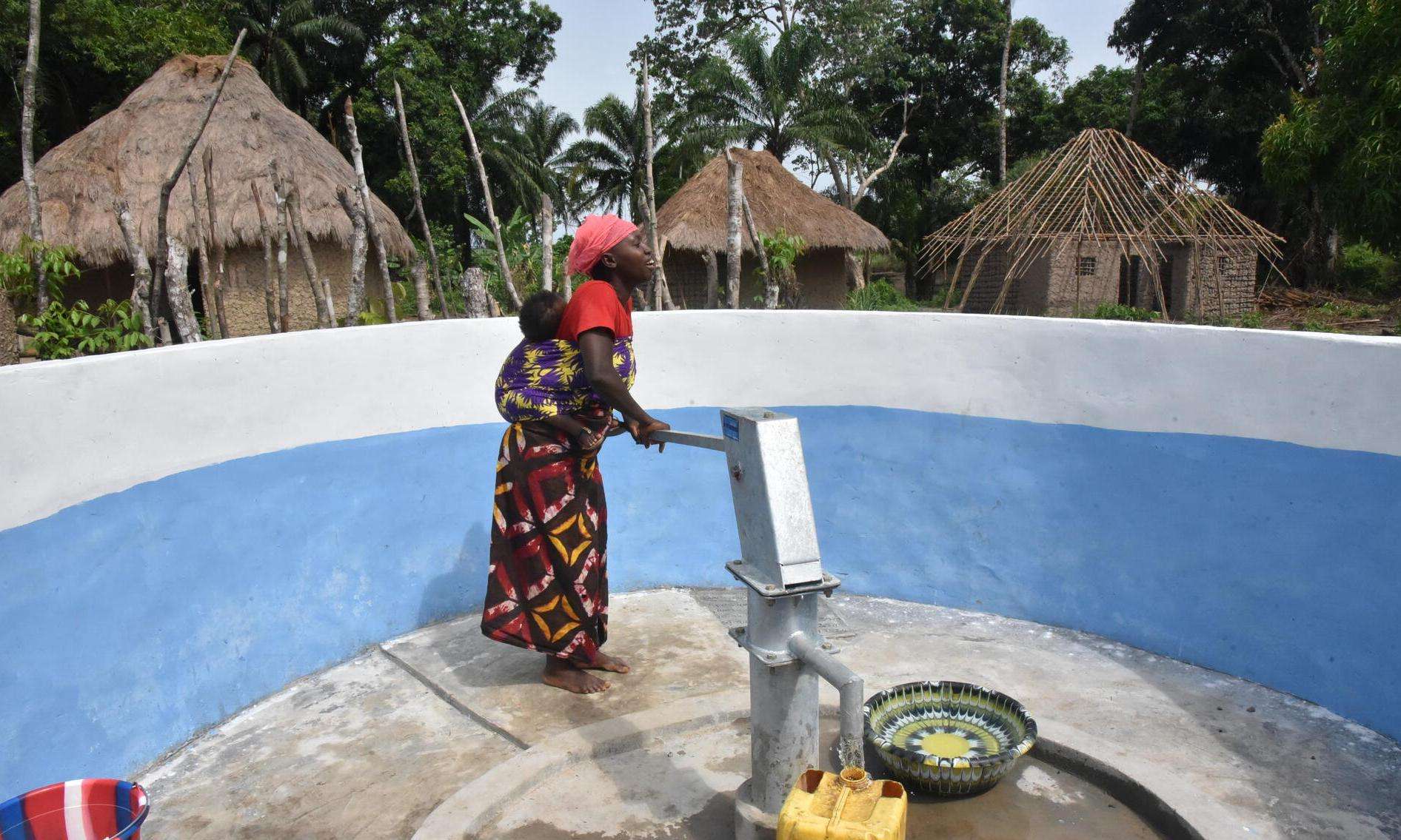 A woman uses a hand pump to get safe drinking water in Sierra Leone. 