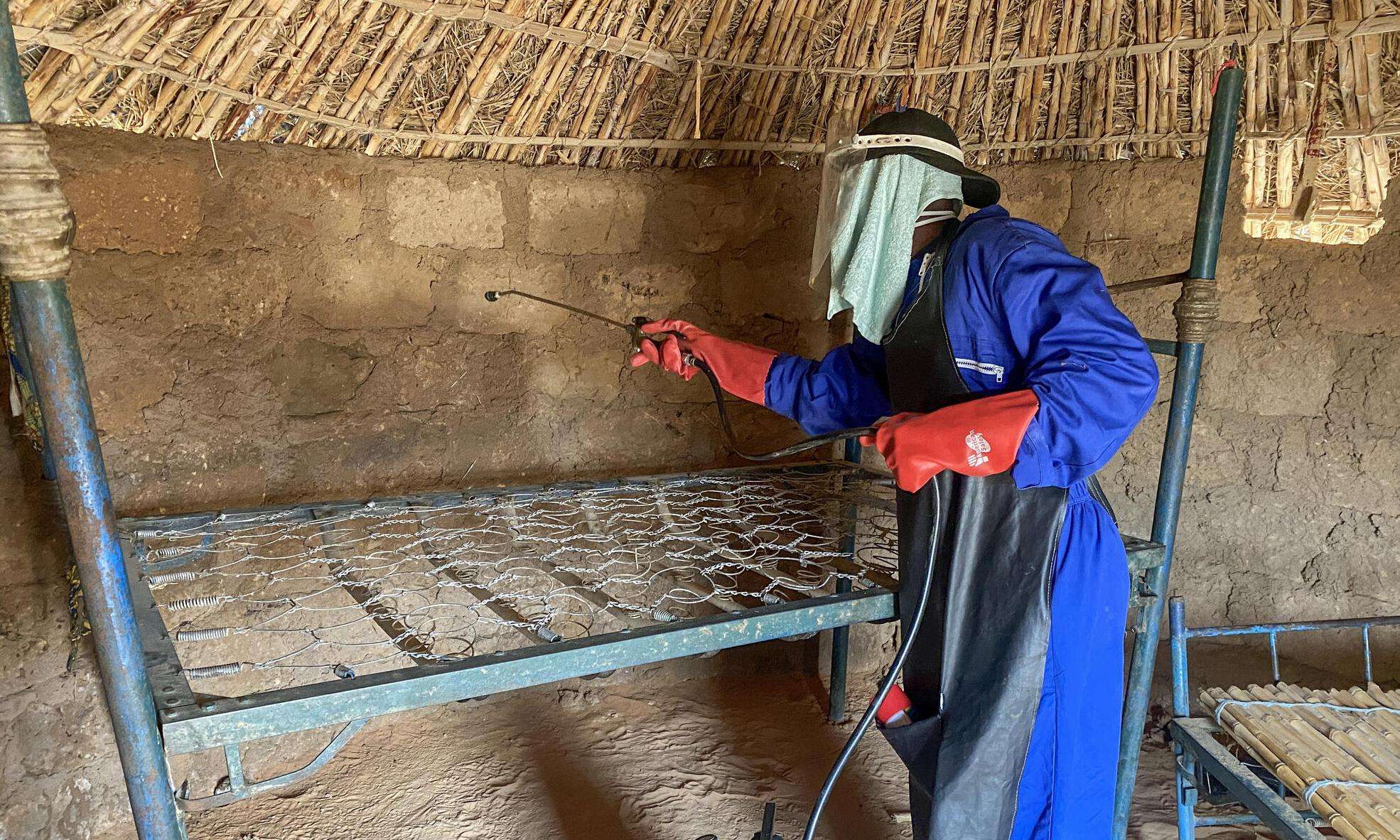 A person sprays pesticide inside a house in Niger. 