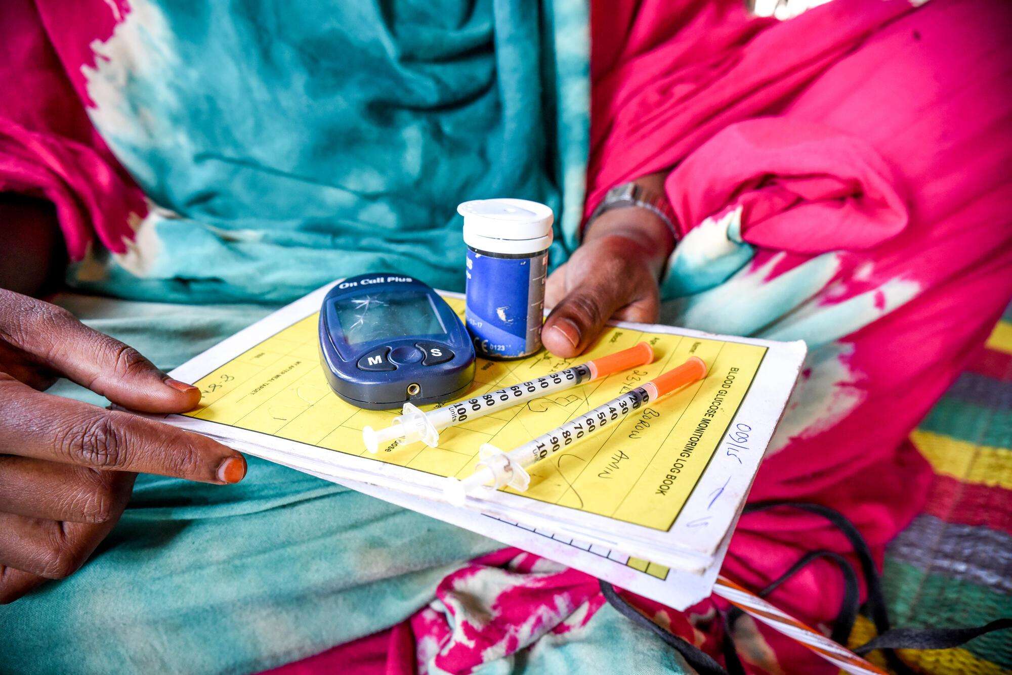 A woman holds her diabetes medications including insulin pens.