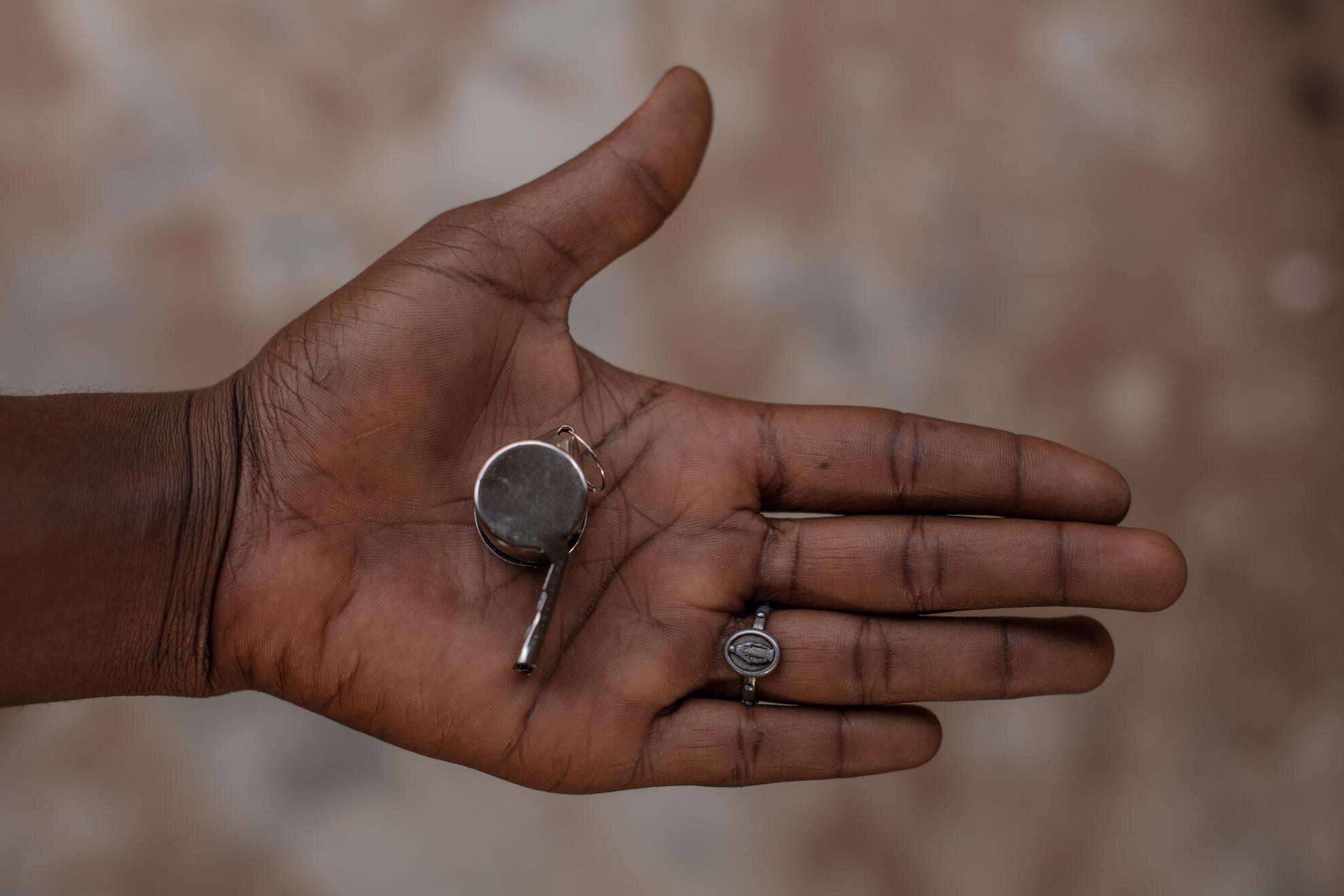 An open hand holding a whistle for protection from sexual violence in Nigeria.