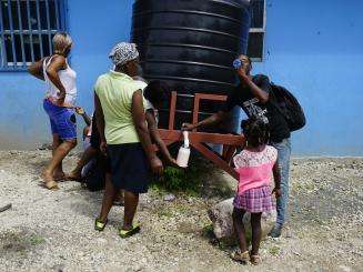 Displaced Haitians collect water.