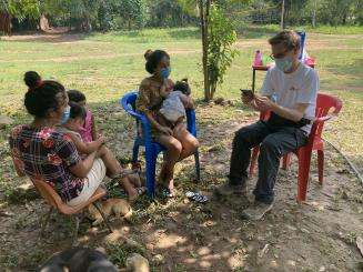 MSF staff is sitting with two women and two children. 