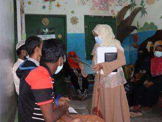 A medic speaks to a group of patients who wait 