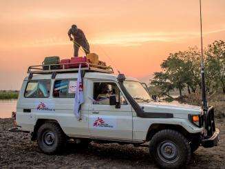 In a remote area of South Sudan, an MSF logistician, attaches to the roof of a 4x4, the equipment that a mobile clinic team has just brought back after a day of mobile boat clinics.