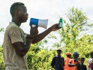 Distribution of NFI in remote areas Abel Mauro Antonio, health promotor explains to the population how to use ceterza to decontaminate water in order to drink it.