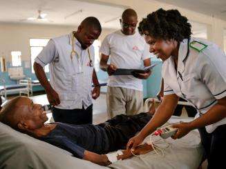 A group of MSF medics gathered around a patient in a hospital bed.