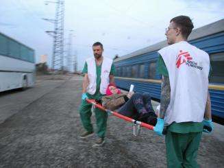 MSF staff members transport a patient from our medical train after its arrival in Lviv from Kramatorsk on April 7, 2022. The train evacuates patients in need of higher levels of care from hospitals close to the front lines.