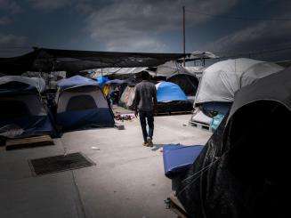 A man walks through the "Senda de Vida" migrant shelter in Reynosa, Mexico, at the US southern border. Hundreds of families relocated to this shelter in May 2022 after a camp that had formed in a public plaza was evacuated and cleared away. At the time, two thousand people were living in the camp, including hundreds of children.