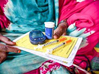 A woman holds her diabetes medications including insulin pens.