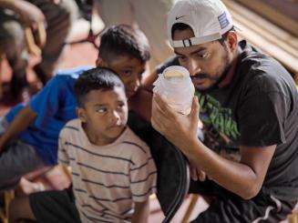 A man and boy look at a jar of mosquitoes to release as part of an MSF project to prevent dengue in Honduras