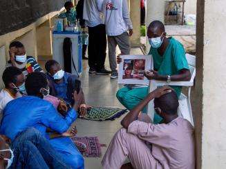 Several MSF medics sit on the floor in a circle in Nigeria where they work on the Kano project.