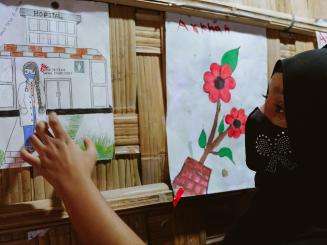 A young Rohingya refugee points to a picture she drew of an MSF doctor in a clinic.