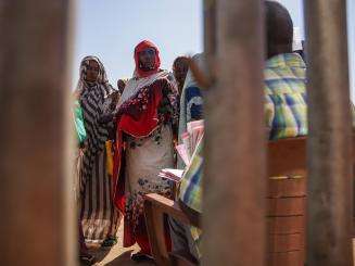 A woman waits in line at a feeding center in Zamzam camp, Sudan. 