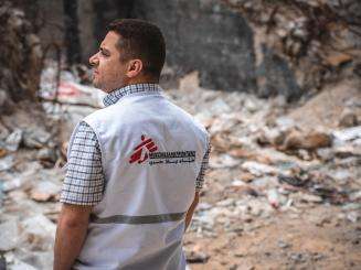 Dr. Sohaib Safi stands in front of the ruins of a residential tower destroyed by an Israeli airstrike in May 2021. r