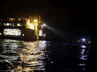 The Geo Barents recue vessel shines a light on a small boat at night in the central Mediterranean.