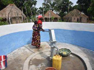 A woman uses a hand pump to get safe drinking water in Sierra Leone. 