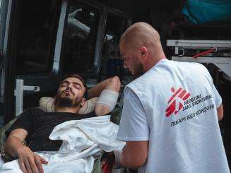 Patient is loaded on a stretcher near an ambulance in Ukraine. 