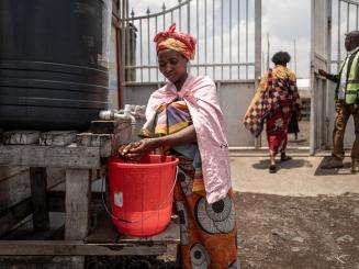 A woman washes her hands at a handwashing stationin a displacement camp in Goma, DRC. 