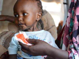 A child eats ready-to-use therapeutic food to treat malnutrition in Sudan.