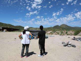 Project Coordinator Belen Ramirez and a 17-year-old boy form Bangladesh look at a helicopter flying overhead at the End of the Wall camp in Arizona.