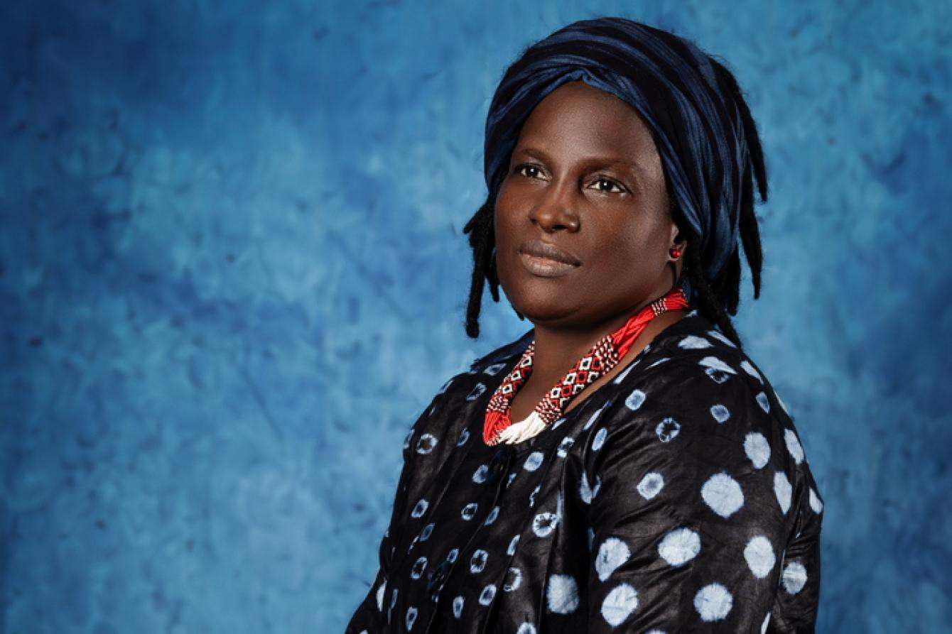 A woman in red necklace against a blue background.