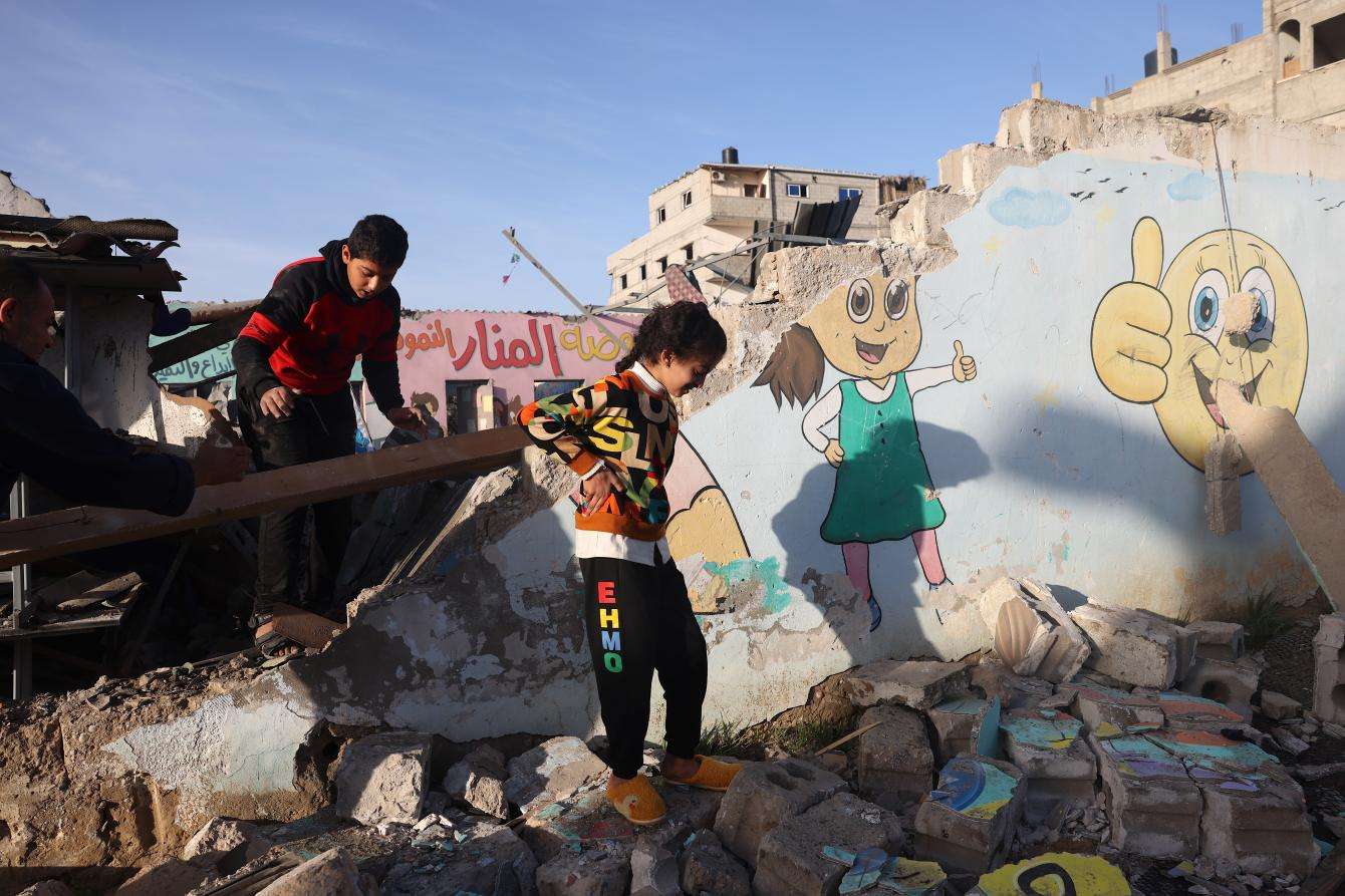 Children walk through the rubble of a destroyed school in Gaza.