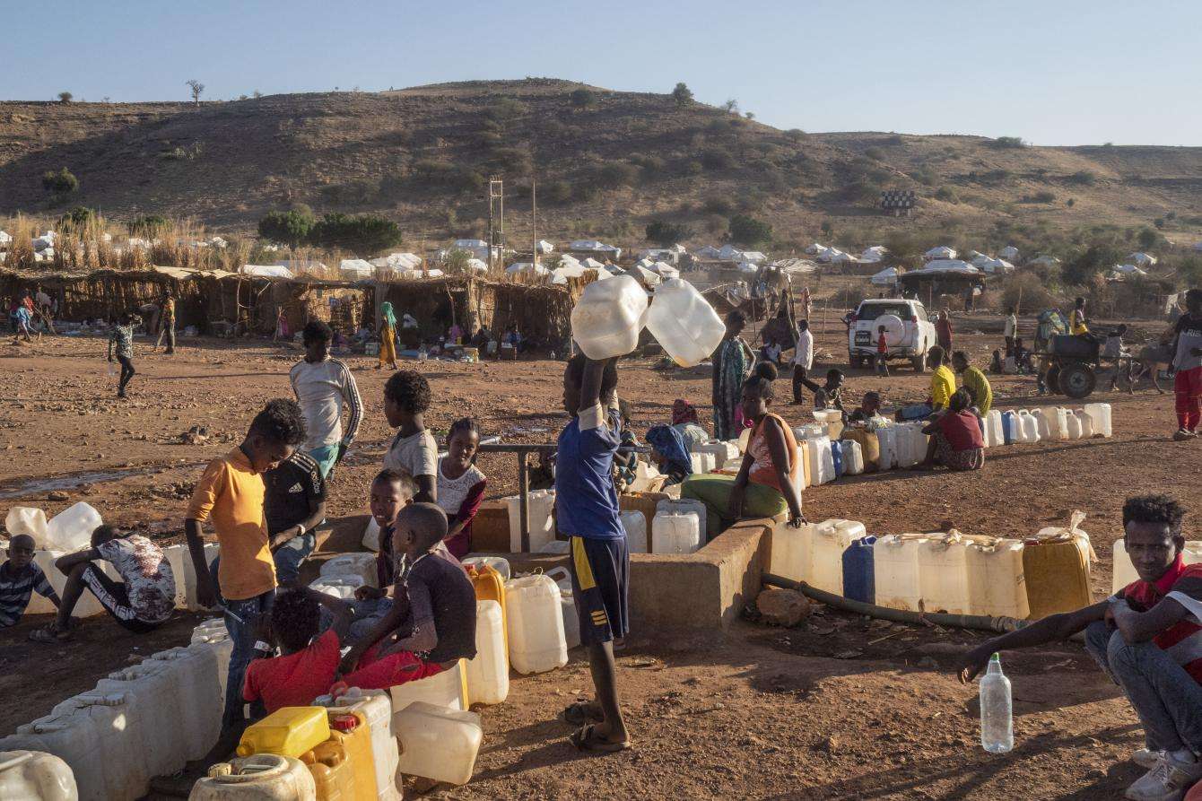 Children standing around water jugs