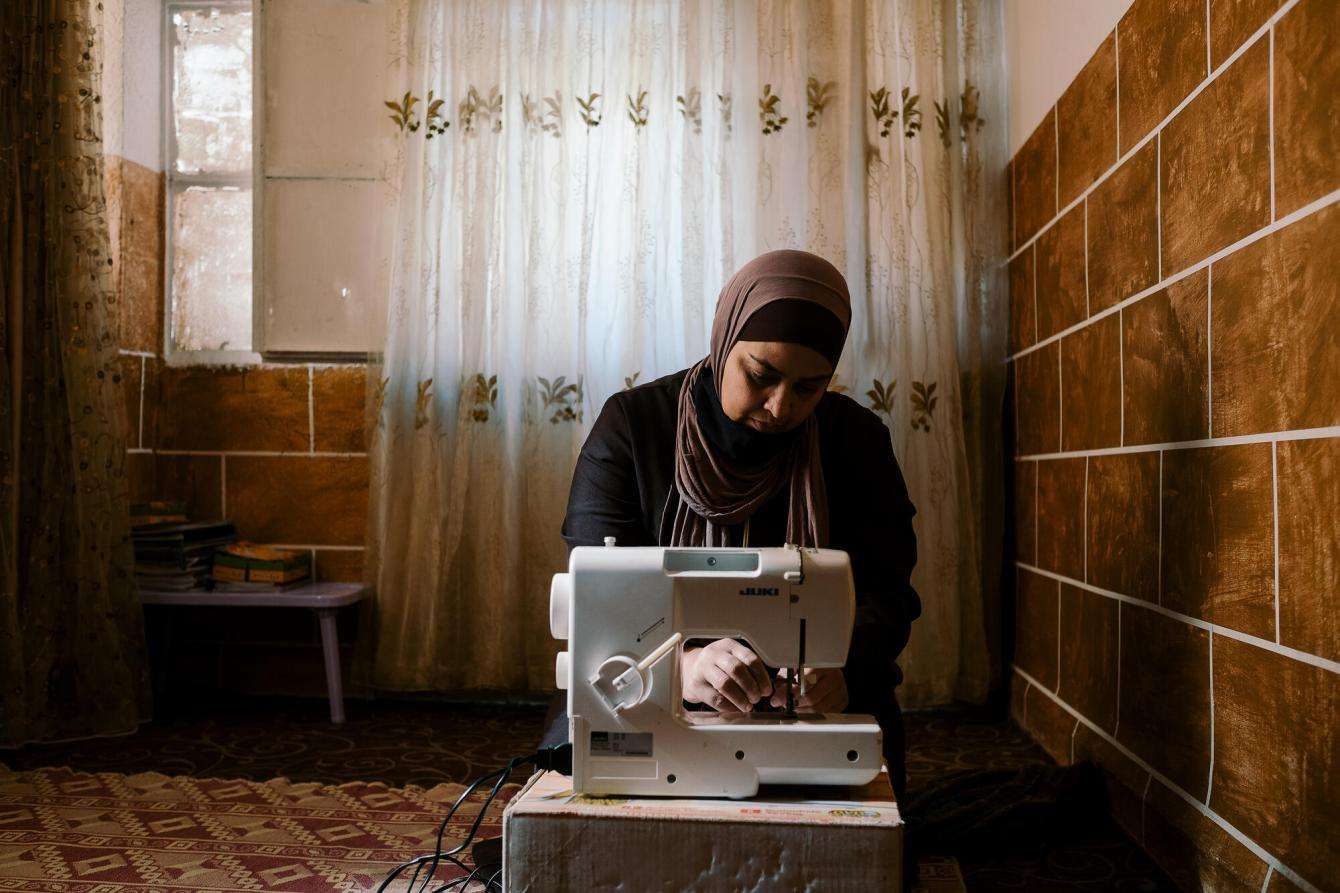 Woman uses a sowing machine in a dark room