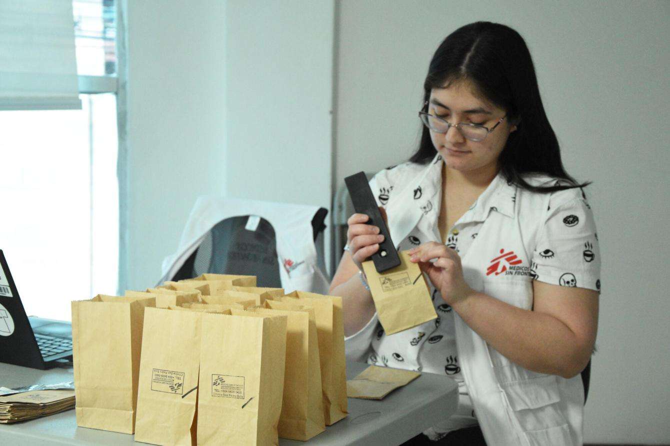 An MSF staff member staples paper bags of medications at the MSF clinic of San Pedro Sula, Honduras.