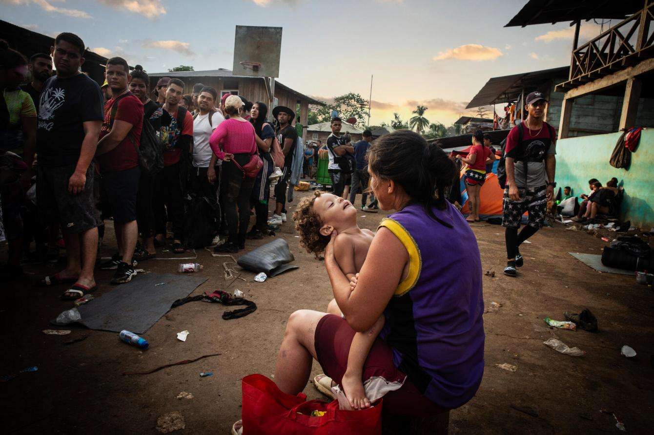 A woman and her child wait for a boat to take them to the Darién jungle.