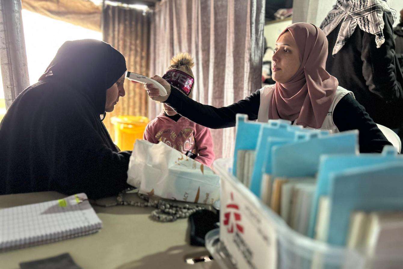 An MSF staff member takes the temperature of a patient in Hebron, Palestine.