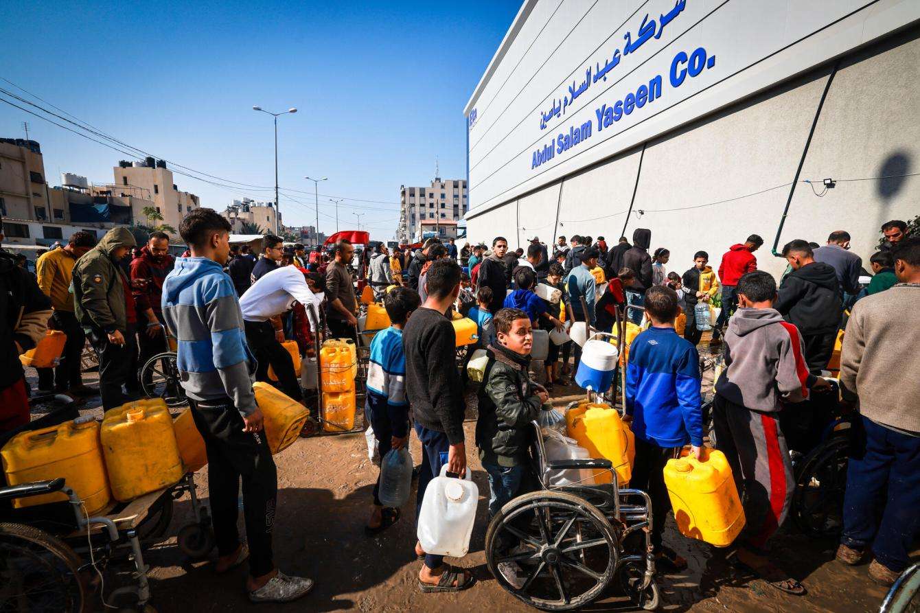 A group of displaced Palestinians waits in front of Abed Al-Salam Yassin company in the Tal Al-Sultan area of the southern Gaza town of Rafah.