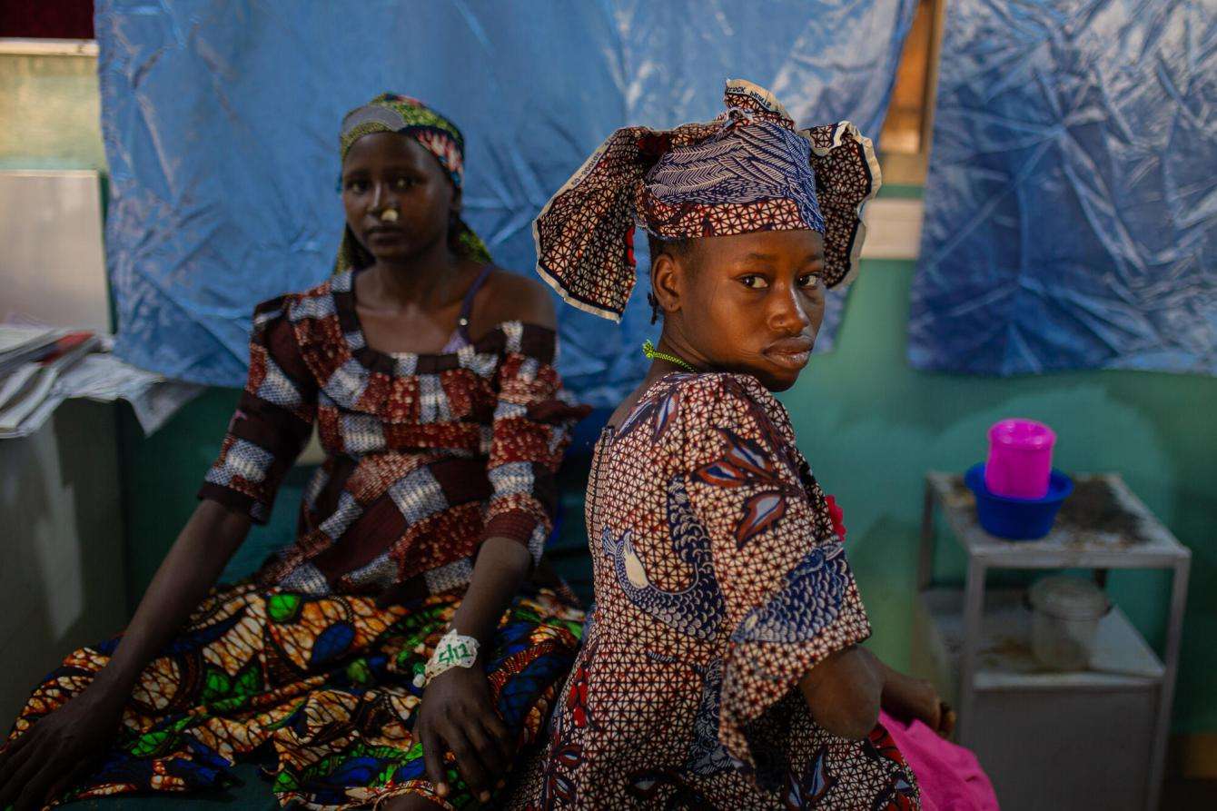 A patient sits on a bed at Jahun Hospital in Nigeria.