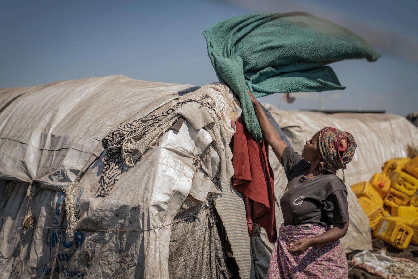 A displaced Congolese woman beside her tent in a camp.