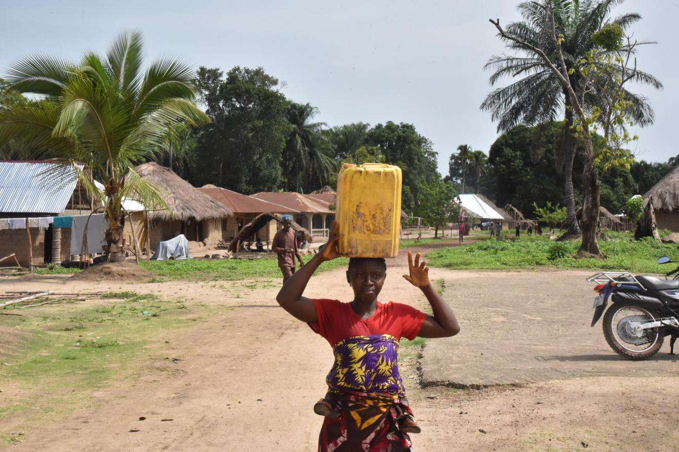 A woman carrying a jerrycan on her head in Sierra Leone