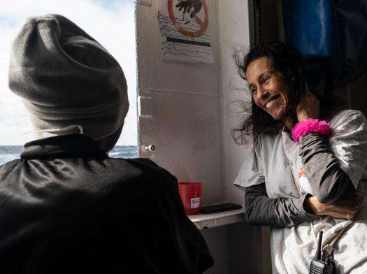 Nejma, MSF cultural mediator, speaks with a patient aboard MSF's search and rescue vessel Geo Barents in the Mediterranean Sea.