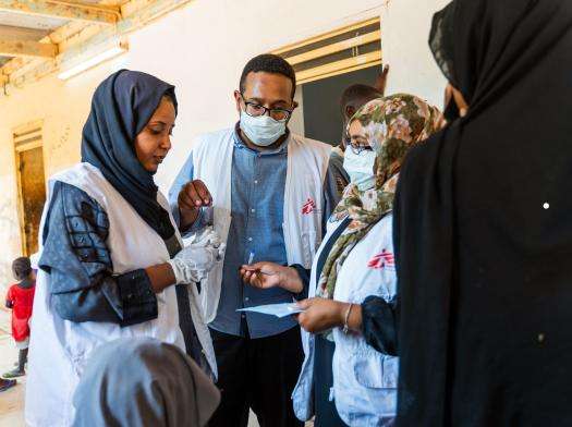 Three MSF medical staff discuss patients at a mobile clinic in Wad Madani, Sudan.