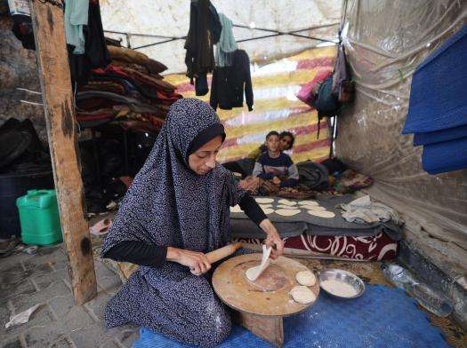 A Palestinian woman makes bread in a tent in Rafah, Gaza.