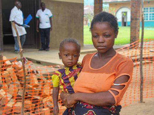 A mother holds her son before a measles vaccination in DRC. 