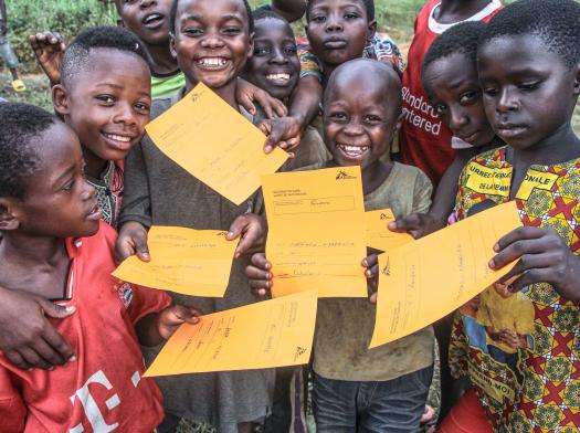 Children in DRC holding vaccine certificates. 