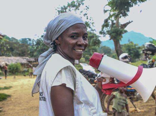 MSF health promoter in DRC uses a megaphone to talk with families. 